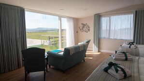 Ein Hotelzimmer mit großem Fenster, einer Couch, einem Bett mit Handtüchern und einem kleinen Tisch.