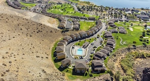 An aerial view of a residential area with houses arranged in a semi-circular pattern around a central swimming pool, with the Columbia River visible in the background. - Luxury @ Crescent Bar! Pool & Free Golf! (Quincy)