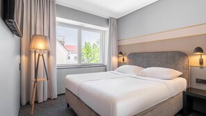 A hotel room with a bed, a window with curtains, a floor lamp, and a wall-mounted lamp. - Fonnental Design Hotel Tallinn (Tallinn)