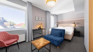 Une chambre d’hôtel moderne équipée d’un lit, d’un bureau, d’une chaise et d’une petite table.
