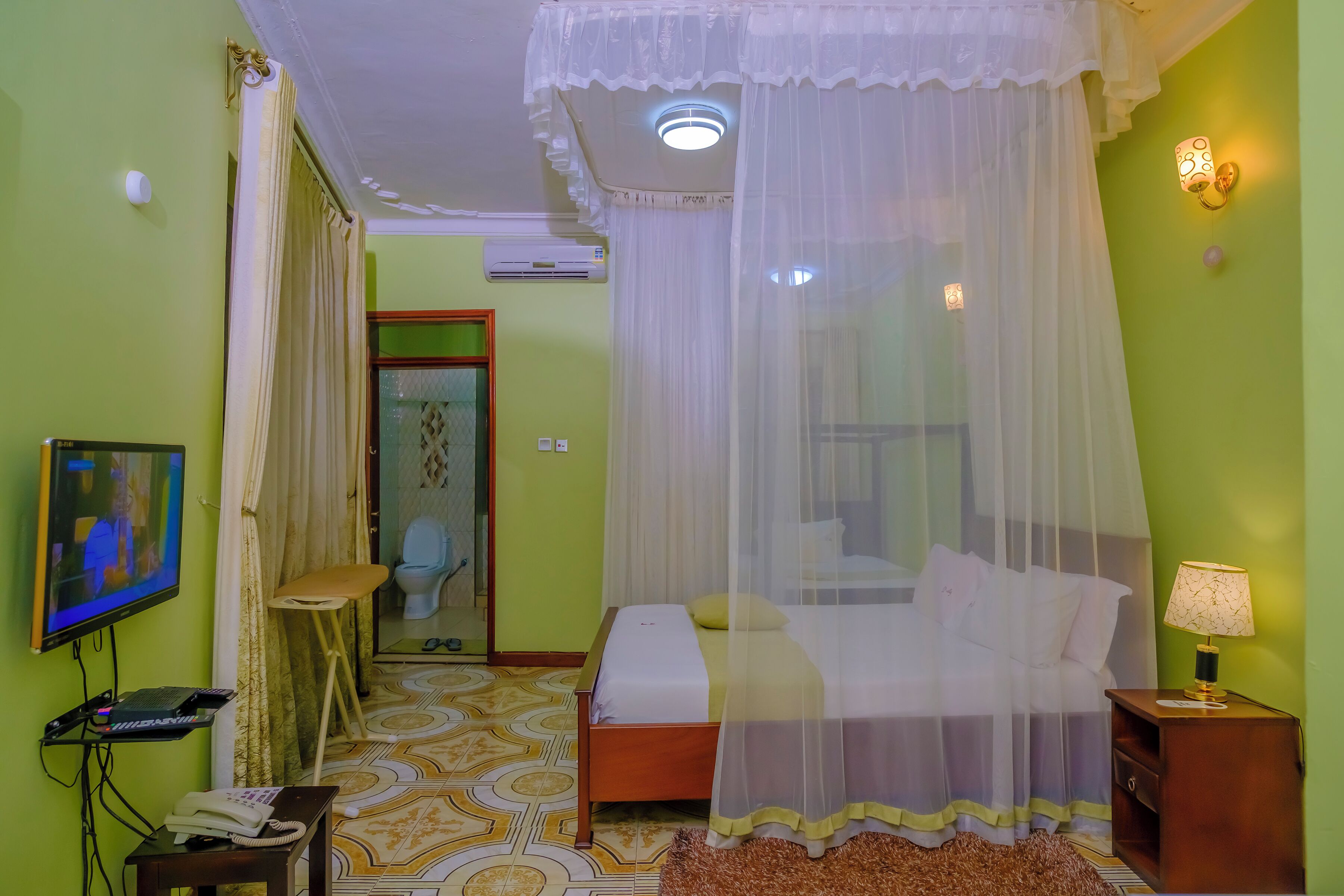 Una habitación con cama, televisión, teléfono y mesita de noche.