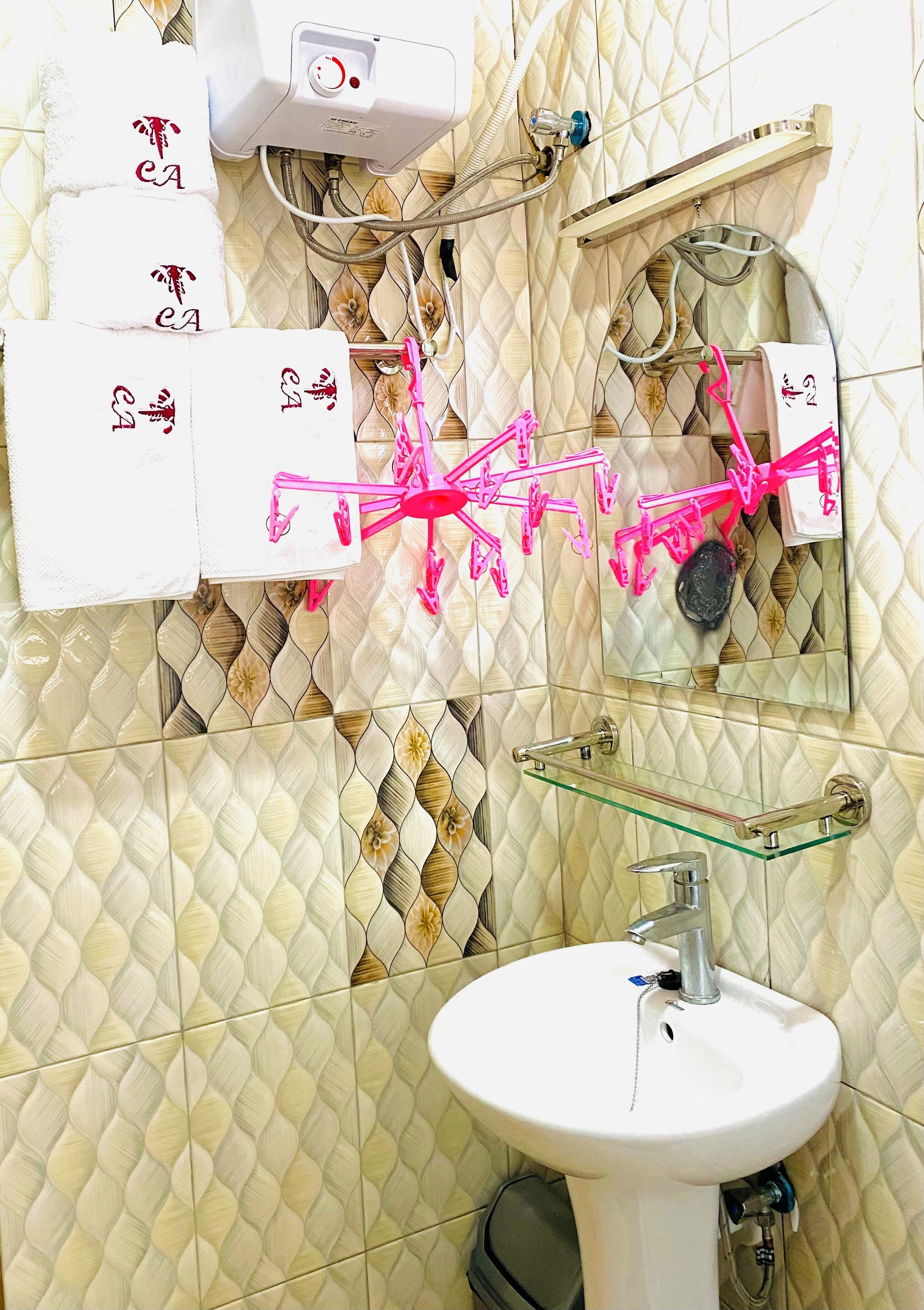 Un baño con un lavamanos blanco, un espejo y un tendedero con pinzas rosas.