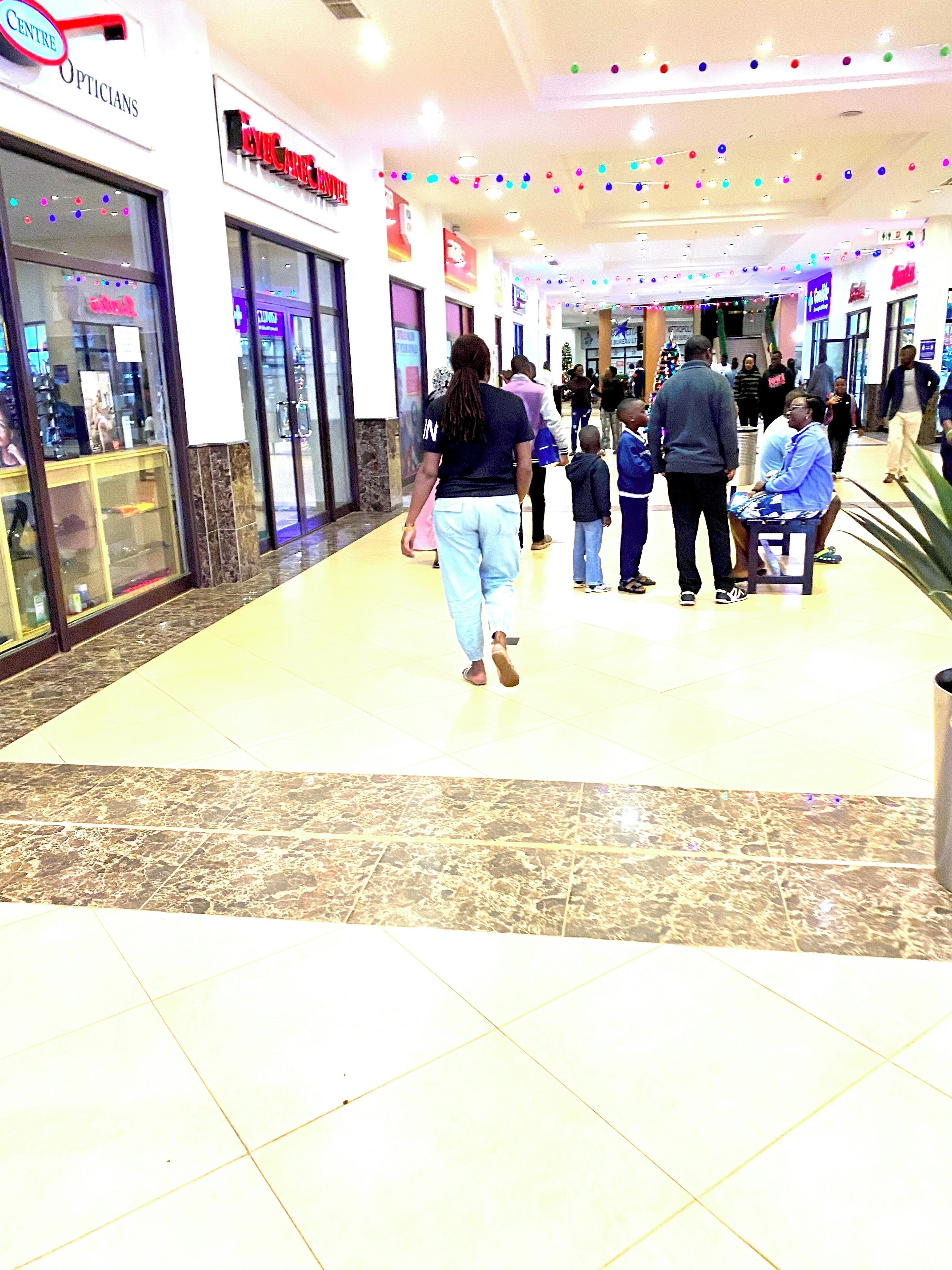 A shopping mall corridor with a 'Centre Opticians' store on the left and a 'Centre Cinemas' on the right.
