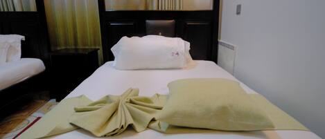 A hotel room with a neatly made bed, a bedside table, and a headboard with curtains.