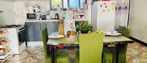 A compact kitchen with a dining area, featuring a microwave, stove, refrigerator, and a table set for four.
