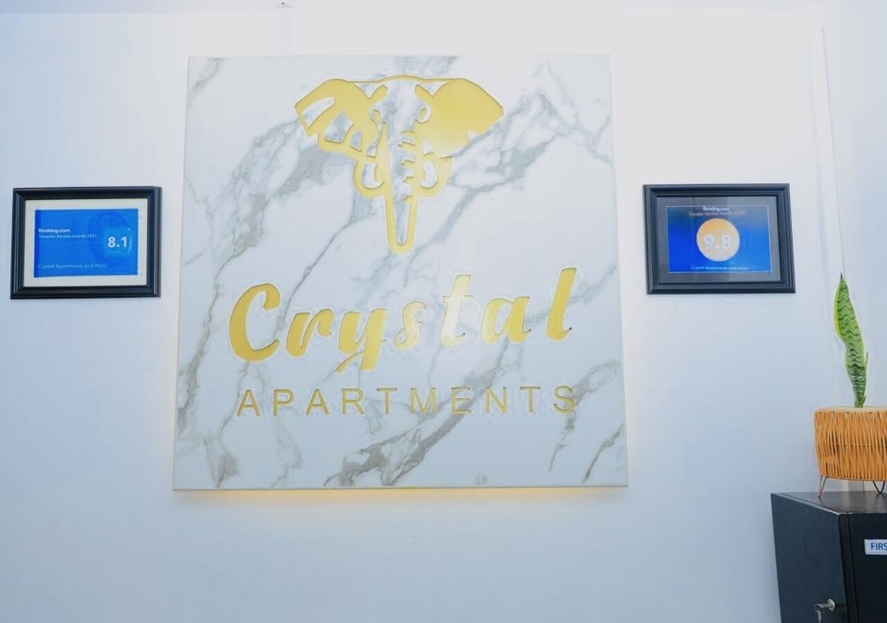 Un mur orné d’une enseigne encadrée portant l’inscription « Crystal Apartments » et de deux certificats encadrés.
