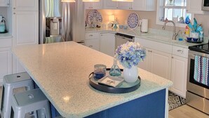 A modern kitchen with white cabinetry, a large island, and pendant lighting. - Private beach access! 2 Bedroom, 2 Full Bath Cottage with many amenities!  (Surfside Beach)