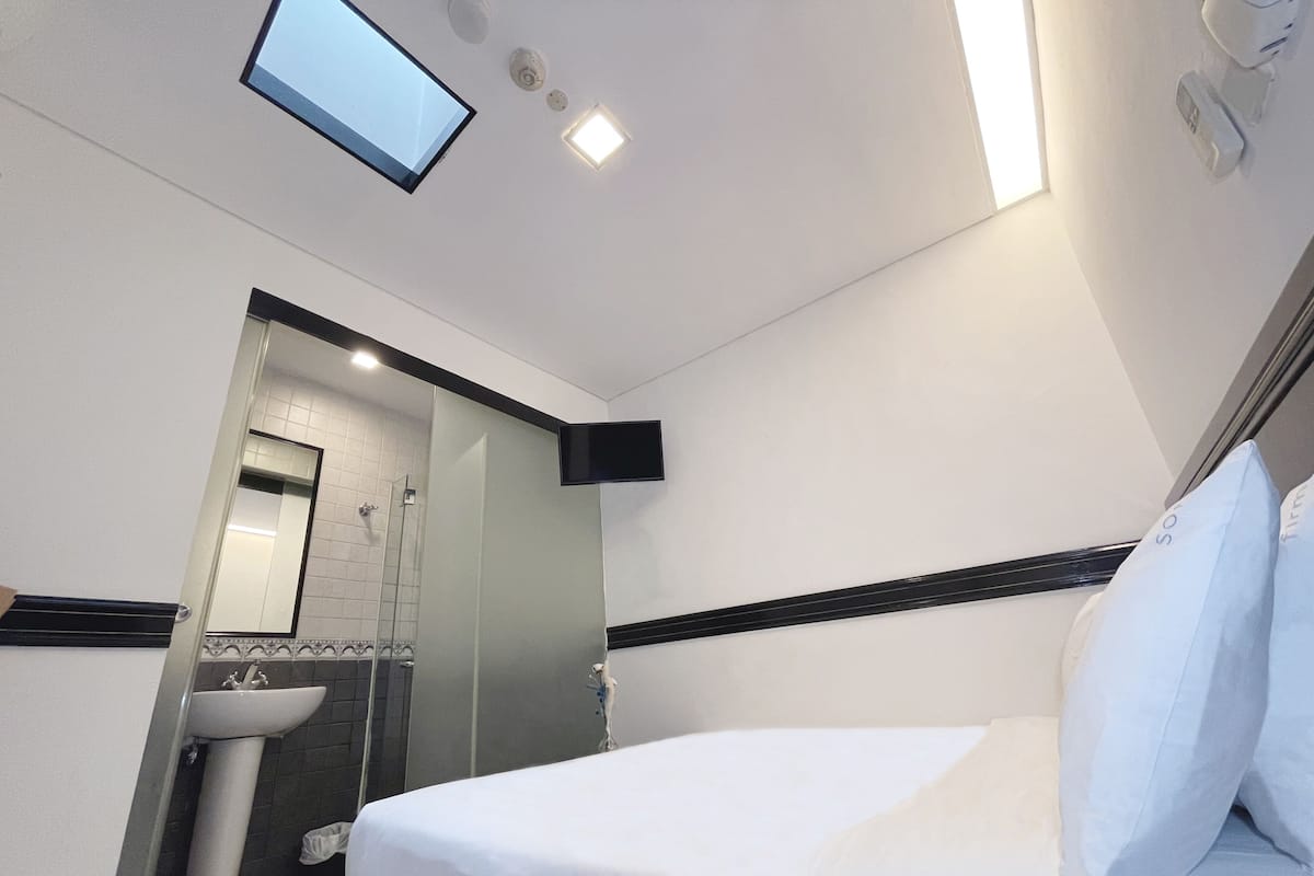 Ein Hotelzimmer mit Bett, Waschbecken und Dusche.