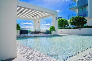 A modern outdoor pool area with a clear view of the sky, a covered seating area, and a tiled pool edge. - Bay & Pool View! Modern 1Bdrm-Miami Design Dist (Miami)