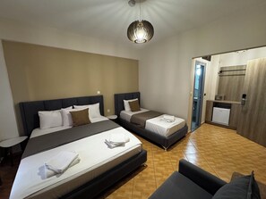 Een hotelkamer met twee bedden, een kleine ronde tafel, een bank, een plafondlamp en een deur naar een badkamer.