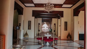 A spacious lobby with a chandelier, a fountain, and a red cushioned seating area. - Borj Des Cascades (Ait Taguella)