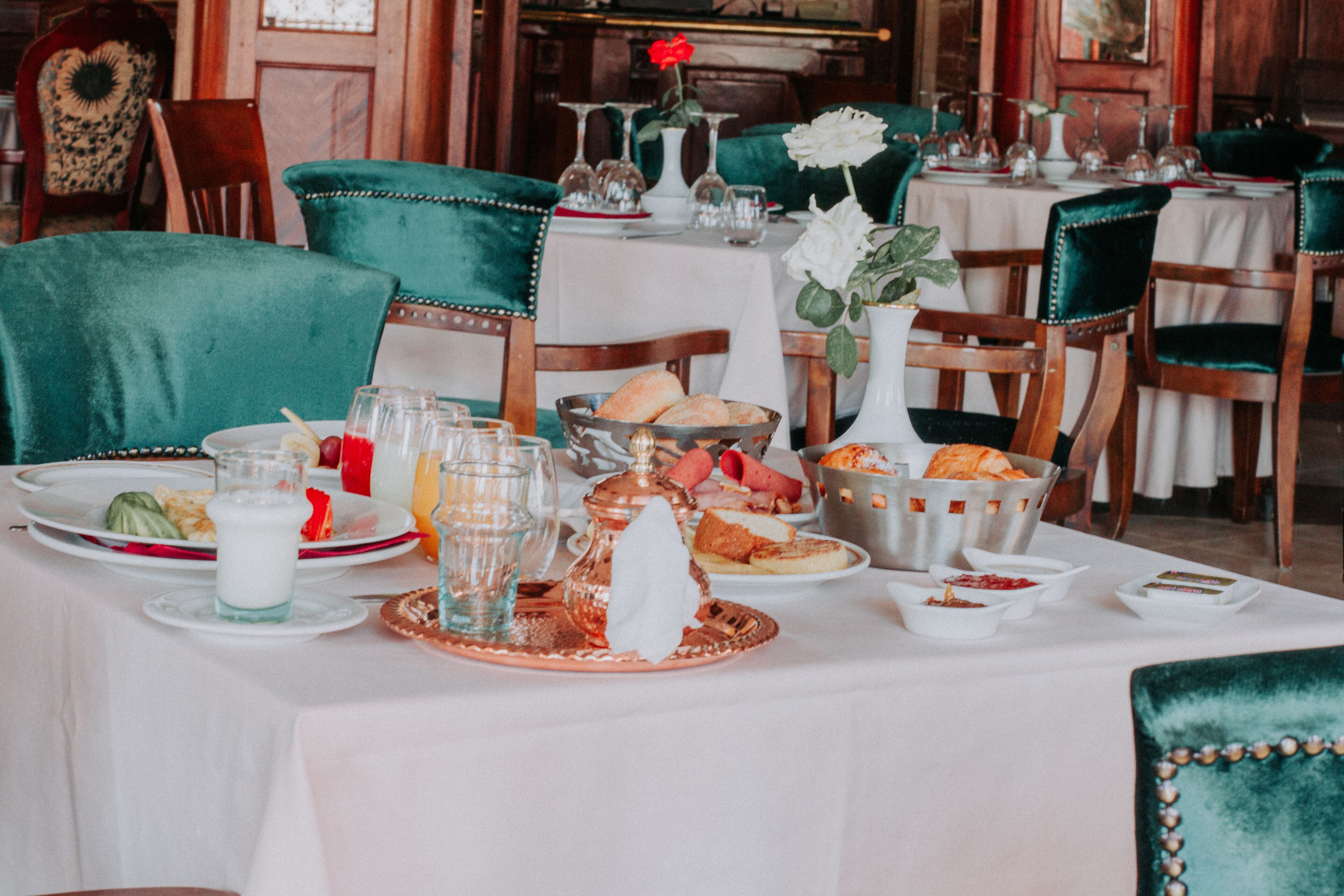 Een eettafel gedekt met verschillende gerechten, glazen en een vaas met bloemen.