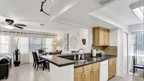 Una cuina moderna amb una illa central, armaris de fusta i una zona de menjador amb taula i cadires.