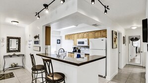 Una cuina moderna amb una illa central, armaris de fusta i un frigorífic d'acer inoxidable.