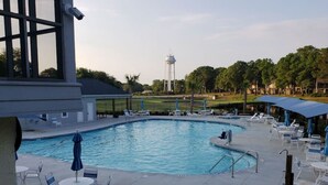 A swimming pool with lounge chairs and umbrellas, surrounded by a landscaped area with trees and a water tower in the background. - Effy's Sunset Serenity Hideaway (Sunset Beach)