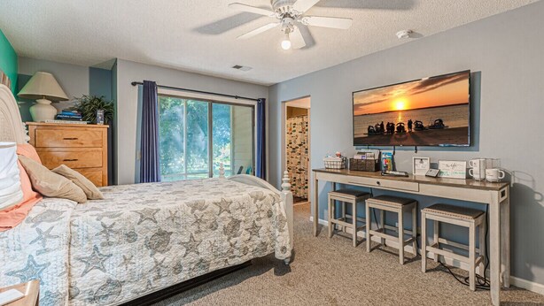 A bedroom with a bed, a desk, a ceiling fan, and a large window. - Effy's Sunset Serenity Hideaway (Sunset Beach)