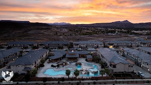 Un resort con varias construcciones, una piscina y montañas al fondo.