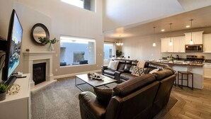 Una sala moderna con chimenea, un sofá grande y una televisión.