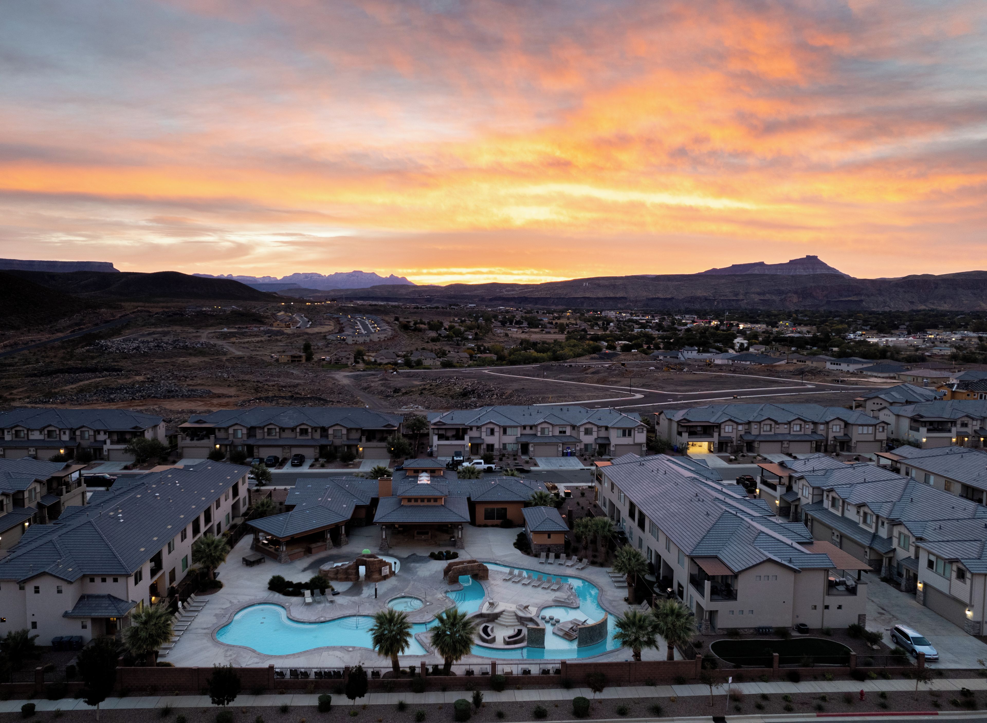A resort with multiple buildings, a swimming pool, and a mountainous backdrop.