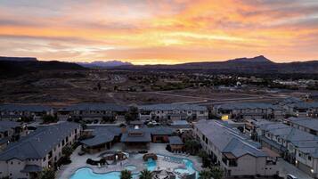 A resort with multiple buildings, a swimming pool, and a mountainous backdrop.
