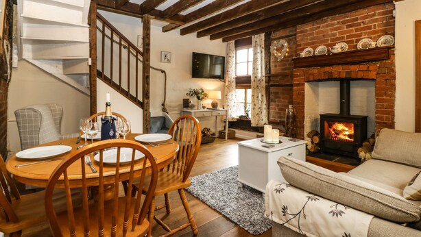 Una sala de estar acogedora con chimenea, muebles de madera y una escalera que sube a otro nivel.