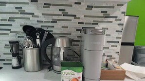 A kitchen counter with a coffee maker, a thermos, a box of Truvia, and a kettle. - A Lovely Modern Retreat for Your Perfect Stay (Hayward)
