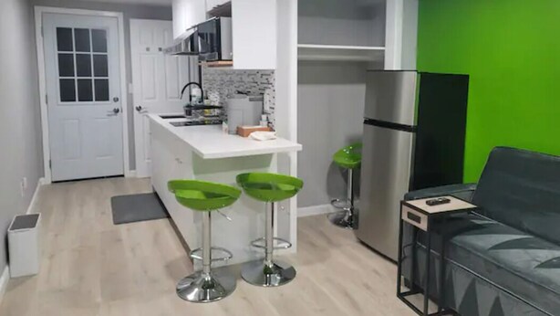 A modern kitchen with white cabinets, a stainless steel refrigerator, and green bar stools. - A Lovely Modern Retreat for Your Perfect Stay (Hayward)
