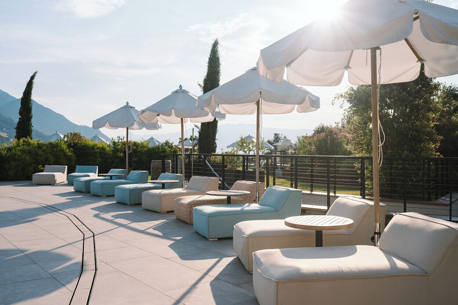 A rooftop terrace with outdoor seating and umbrellas, overlooking a mountainous landscape.