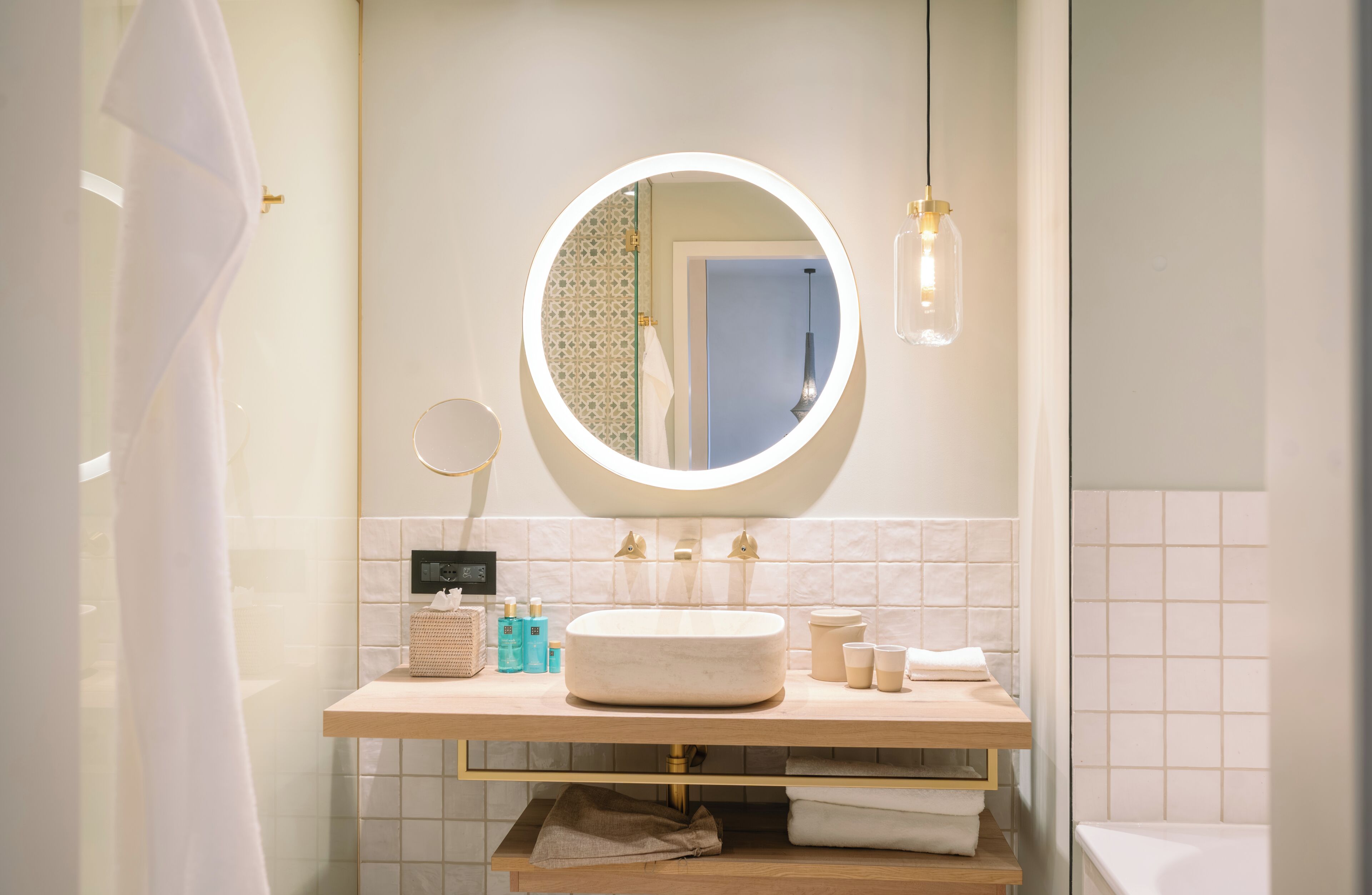 Un bagno con uno specchio rotondo, un lavandino e un portascopino.