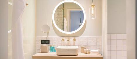 A bathroom with a round mirror, a sink, and a towel rack.