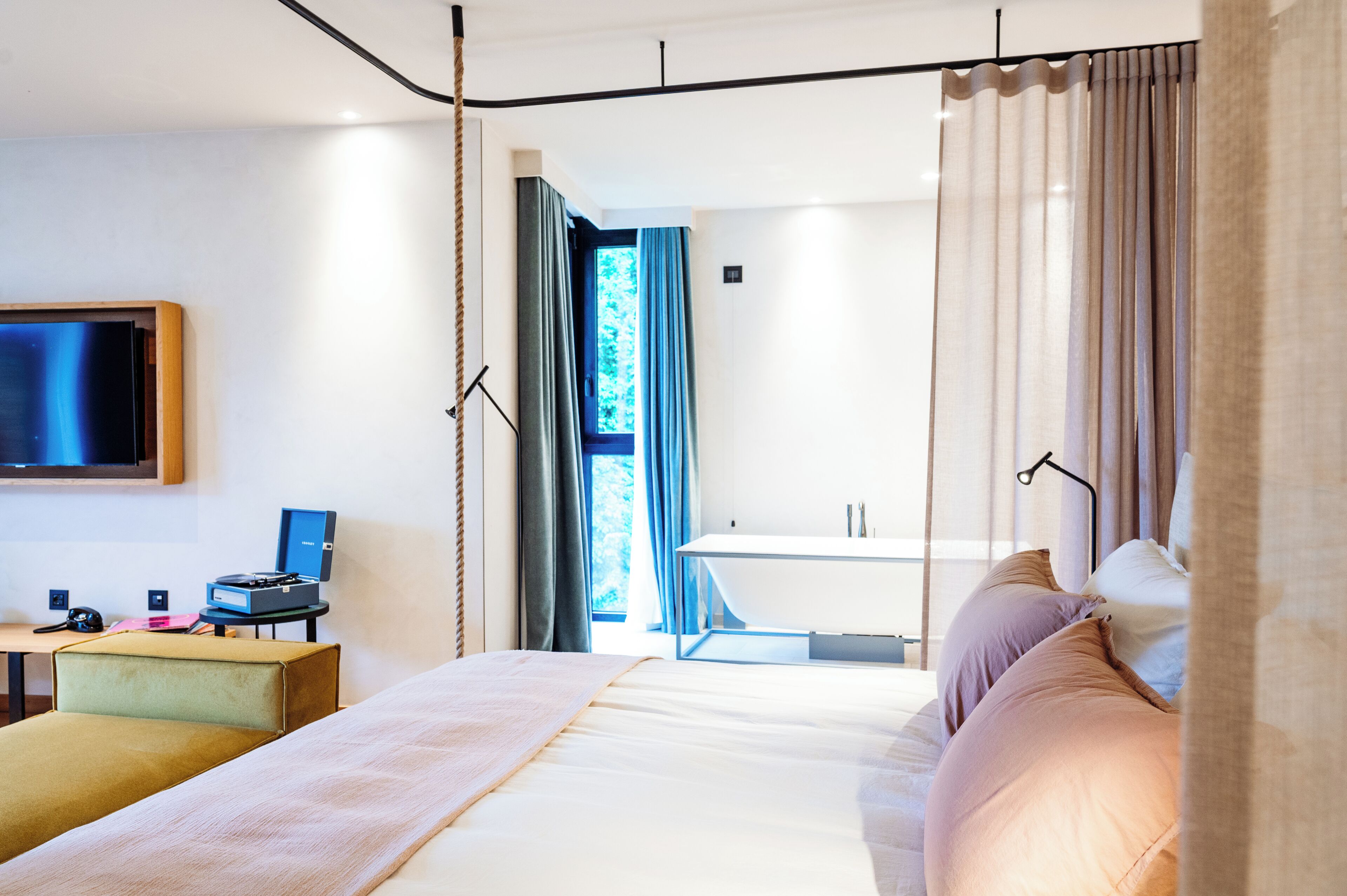 Une chambre d’hôtel moderne, dotée d’un grand lit, d’un bureau avec un ordinateur et d’un téléviseur fixé au mur.