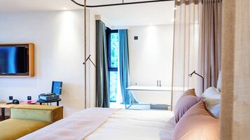 Une chambre d’hôtel moderne, dotée d’un grand lit, d’un bureau avec un ordinateur et d’un téléviseur fixé au mur.