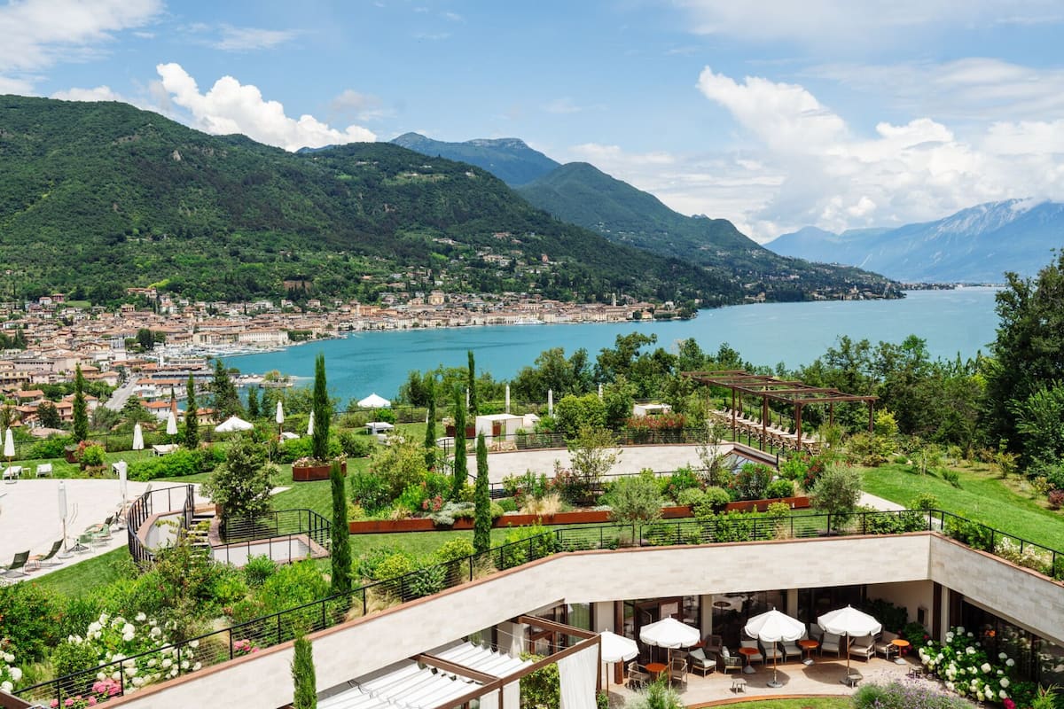 A hotel with outdoor seating overlooking a lake and mountains.