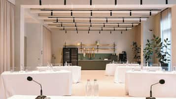 Un salón de conferencias con mesas dispuestas para una reunión, equipado con micrófonos y botellas de agua.