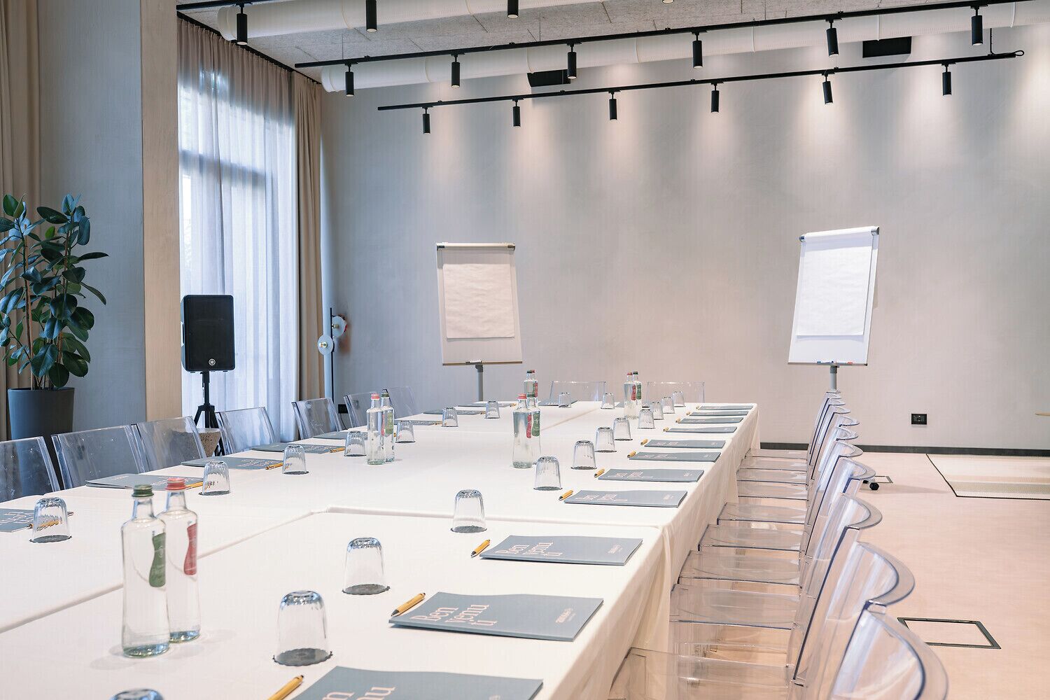 Een vergaderruimte met een lange tafel, stoelen, een projecter en een whiteboard.