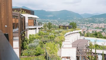 A modern hotel with a rooftop garden, a swimming pool, and a view of the city and mountains.