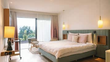 A bedroom with a bed, bedside tables, a desk, a chair, and a view through a large window.