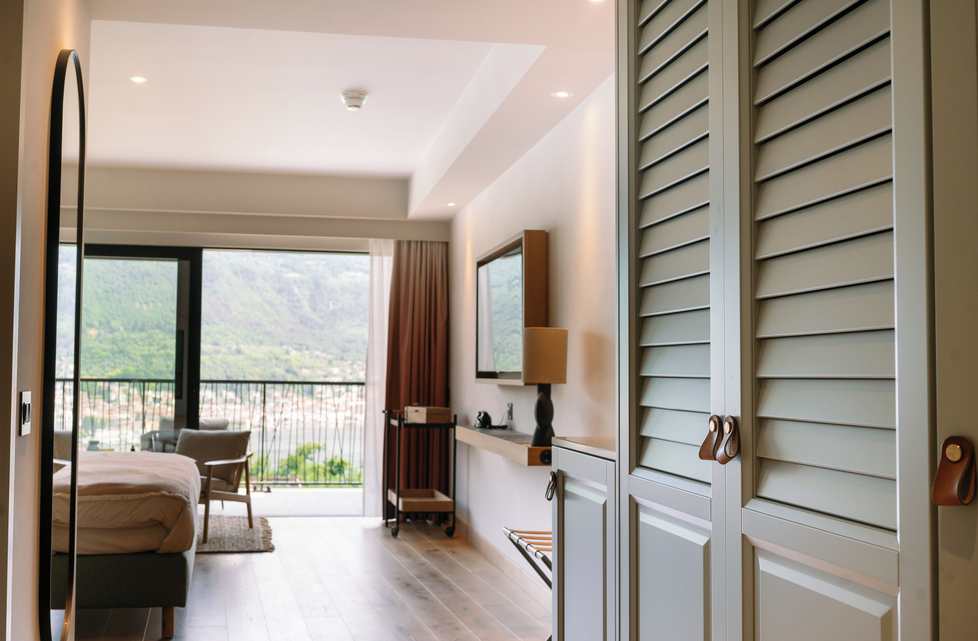 Una habitación de hotel moderna con balcón, cama, escritorio y una silla.