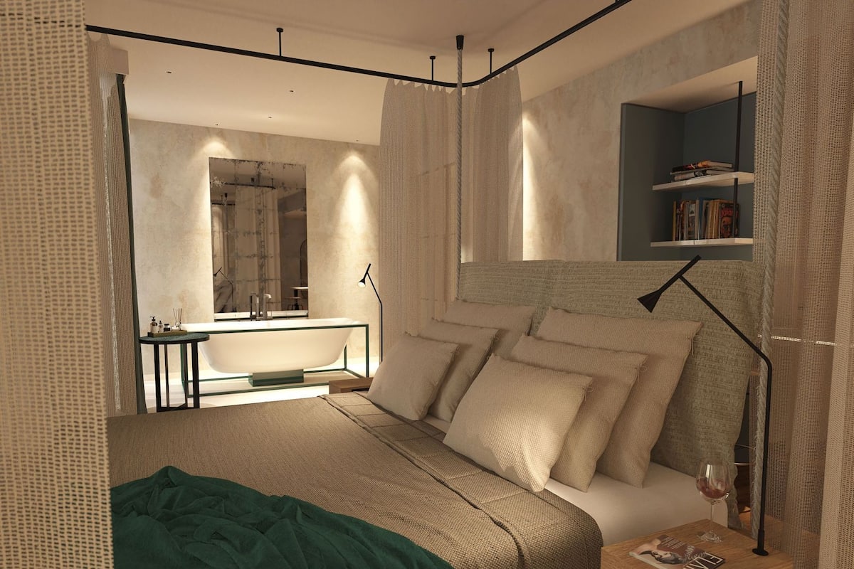 A modern bedroom with a large bed, bedside tables, a mirror, and a bookshelf.