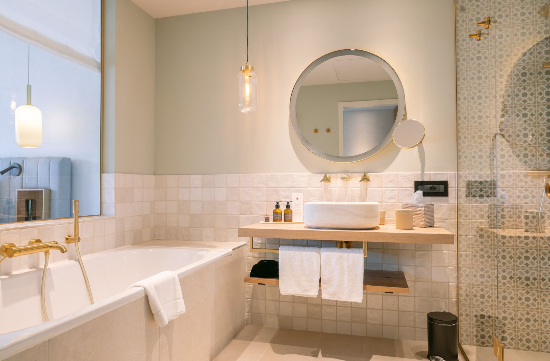 Un bagno moderno con una vasca freestanding, uno specchio rotondo e un mobile lavabo con un lavandino grande.