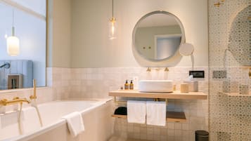 Un bagno moderno con una vasca freestanding, uno specchio rotondo e un mobile lavabo con un lavandino grande.