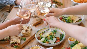 Un grupo de personas brindando con copas de vino alrededor de una mesa de madera con varios platos.