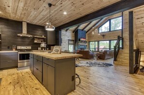 Una cocina amplia con una isla central, techo de madera y ventanas grandes.