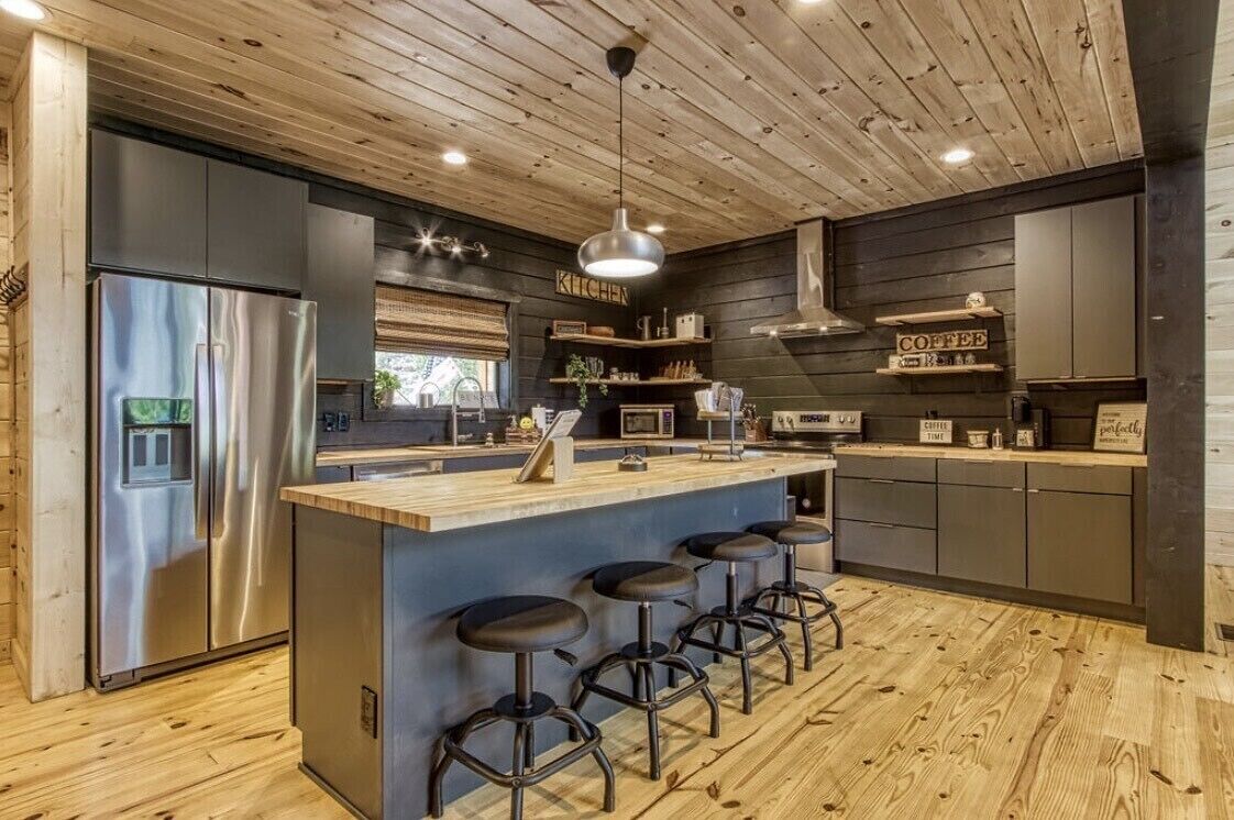 A modern kitchen with a central island, bar stools, and stainless steel appliances.