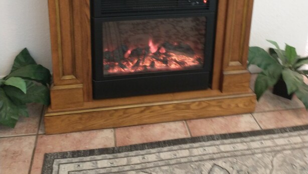 A wooden fireplace with a television mounted above it.