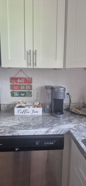 A kitchen with white cabinets, a coffee maker, and a sign that reads 'Coffee Bar.' - Horse N Around (Ocala)