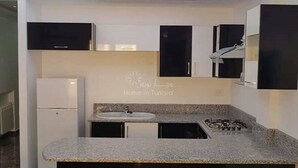 A modern kitchen with a central island, built-in appliances, and a recessed ceiling light. - Nice apartment in soviva (حمام سوسة)