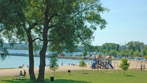 Un parque con un área de juegos, mesas de picnic y vistas al agua.