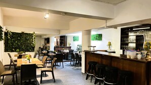 En modern restaurang med en bardel, barnstolar och en grön vägg.