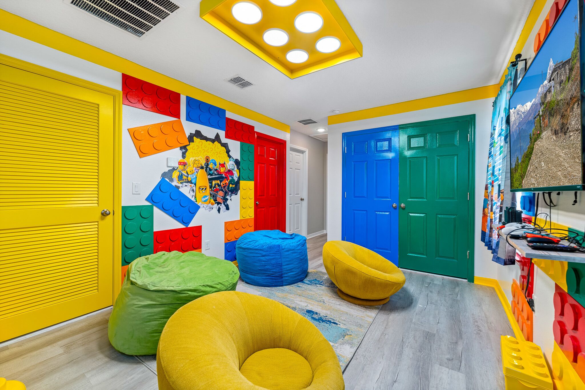 Une pièce aux couleurs vives, ornée d’une décoration murale en LEGO, de portes colorées et de fauteuils en forme de sac de haricots.